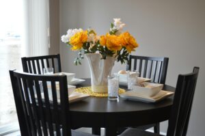 A stylish dining area featuring a round table with vibrant floral centerpiece and modern tableware.